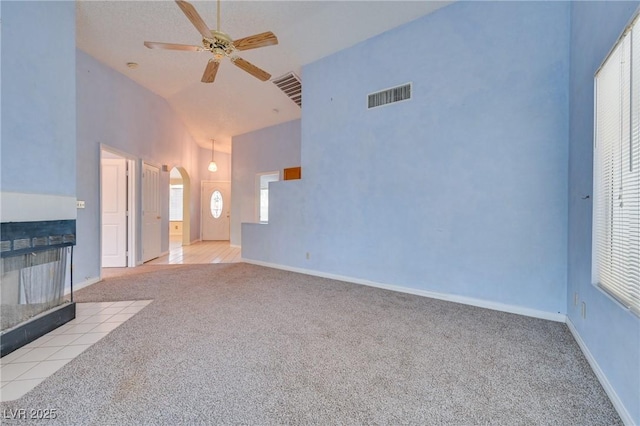 unfurnished living room with ceiling fan, a fireplace, high vaulted ceiling, and light carpet