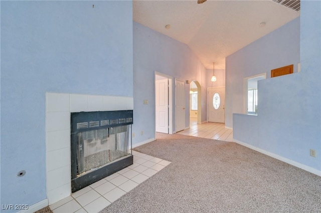 unfurnished living room with lofted ceiling, a fireplace, and light carpet