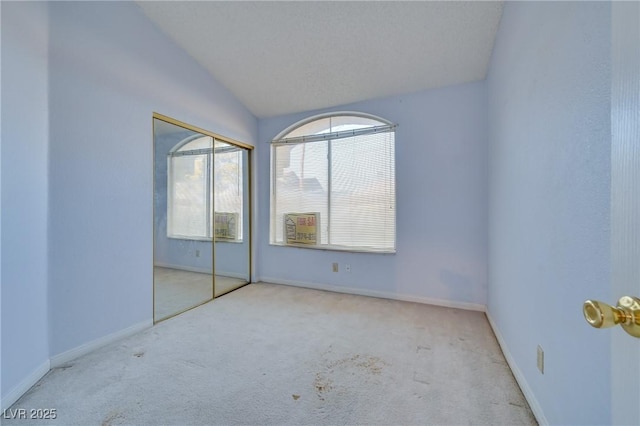 unfurnished bedroom featuring light colored carpet, vaulted ceiling, and a closet