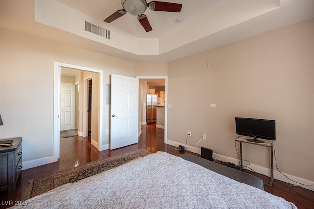 unfurnished bedroom featuring dark hardwood / wood-style floors, ceiling fan, and a raised ceiling