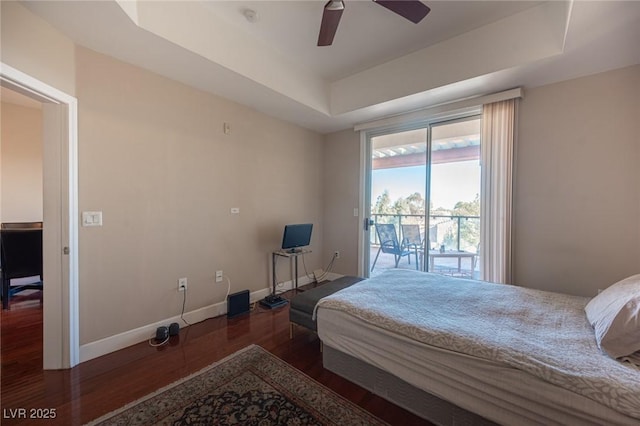 bedroom featuring ceiling fan, access to exterior, dark hardwood / wood-style floors, and a raised ceiling