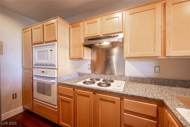 kitchen with light stone countertops, dark hardwood / wood-style flooring, light brown cabinetry, and white appliances