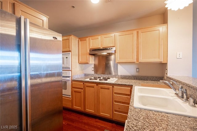 kitchen with light brown cabinetry, sink, white appliances, and dark hardwood / wood-style floors