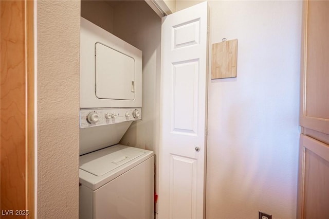 washroom featuring stacked washer / drying machine