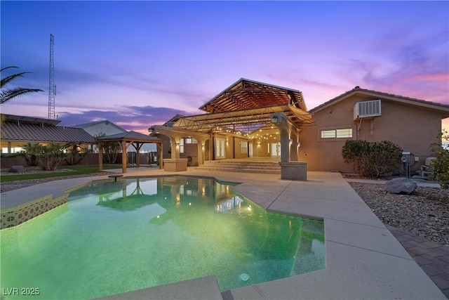 pool at dusk with a gazebo and a patio area