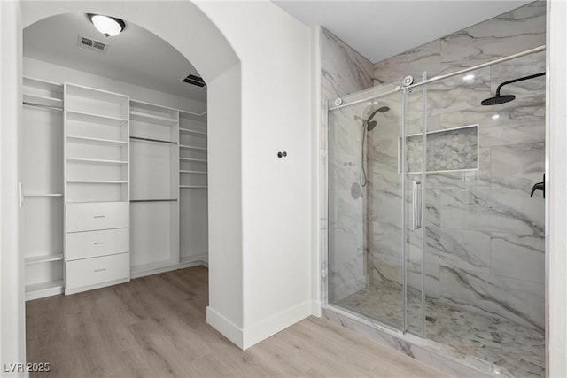 bathroom with a shower with door and wood-type flooring