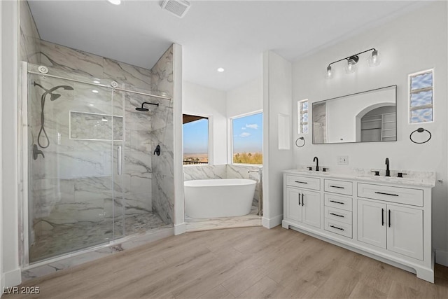 bathroom with independent shower and bath, vanity, and hardwood / wood-style floors