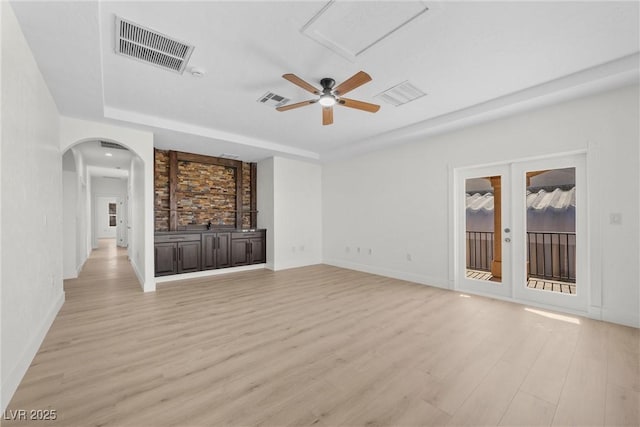 unfurnished living room with french doors, ceiling fan, a raised ceiling, and light hardwood / wood-style floors