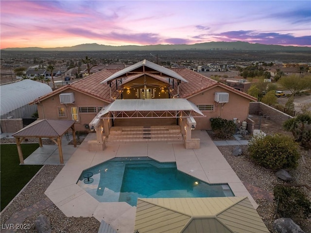 back house at dusk with a gazebo, a mountain view, and a patio