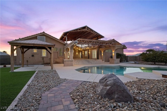 pool at dusk with a gazebo and a patio area