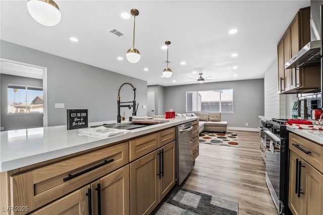 kitchen featuring gas stove, decorative light fixtures, wall chimney range hood, ceiling fan, and stainless steel dishwasher