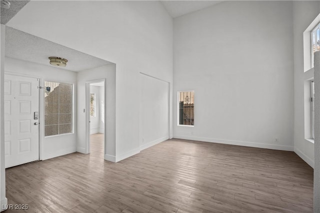 entryway with wood-type flooring and a towering ceiling