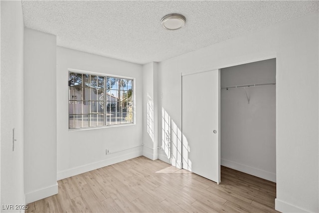 unfurnished bedroom with a textured ceiling, a closet, and light hardwood / wood-style floors