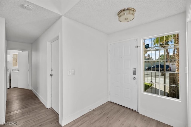 entryway featuring washer / clothes dryer, a textured ceiling, and light hardwood / wood-style flooring