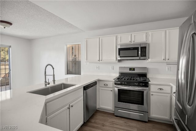 kitchen featuring white cabinets, kitchen peninsula, sink, and stainless steel appliances