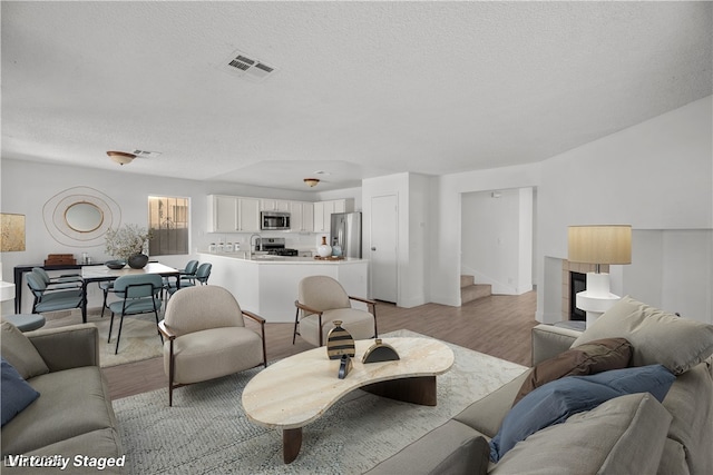 living room with a textured ceiling, light hardwood / wood-style floors, and sink