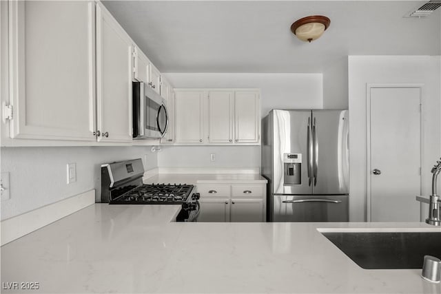 kitchen with stainless steel appliances, white cabinets, and sink