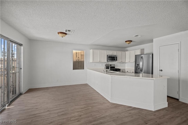 kitchen with kitchen peninsula, sink, stainless steel appliances, and white cabinetry