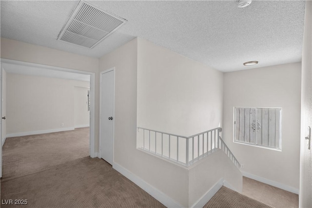 hallway with a textured ceiling and carpet flooring