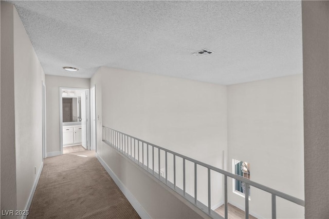 corridor with carpet and a textured ceiling