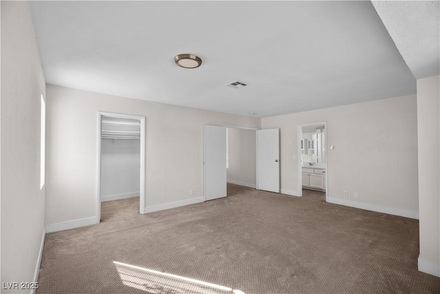 unfurnished bedroom with a spacious closet, a closet, carpet, and connected bathroom