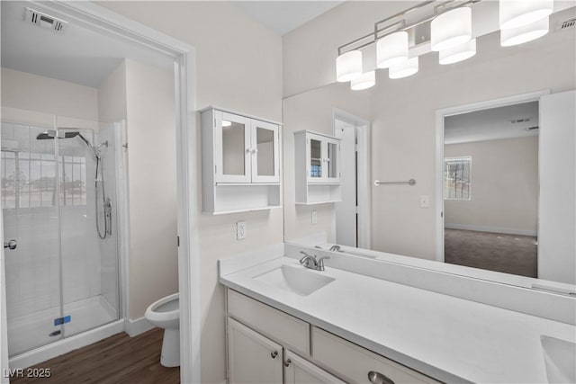 bathroom with an enclosed shower, vanity, toilet, and hardwood / wood-style flooring