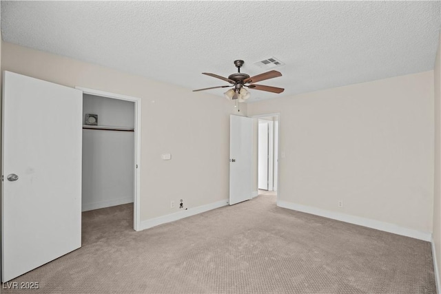 unfurnished bedroom featuring ceiling fan, light colored carpet, a textured ceiling, and a closet