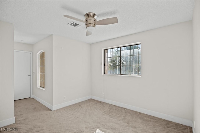 carpeted spare room featuring a textured ceiling and ceiling fan