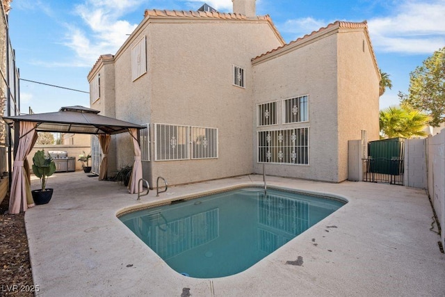 back of property featuring a fenced in pool, a patio area, and a gazebo