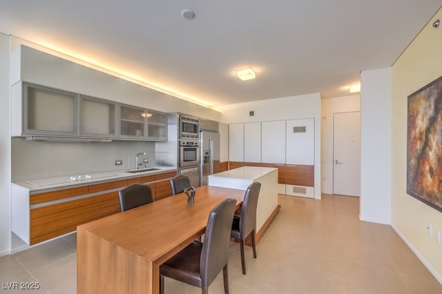 kitchen with sink, appliances with stainless steel finishes, a center island, light tile patterned flooring, and decorative backsplash