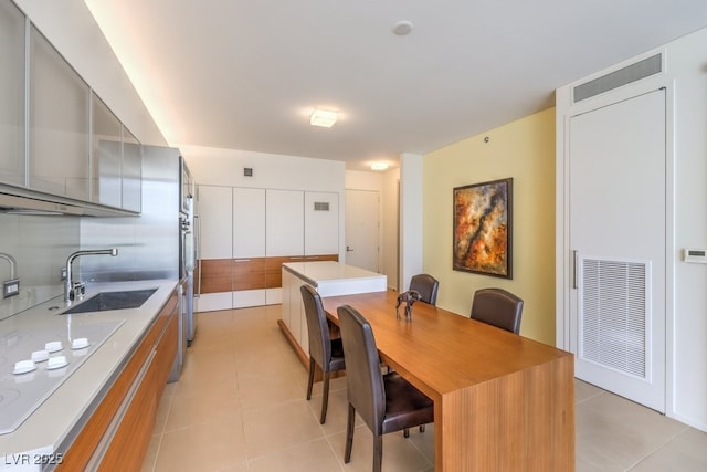 kitchen featuring sink, light tile patterned floors, tasteful backsplash, a kitchen island, and white electric stovetop