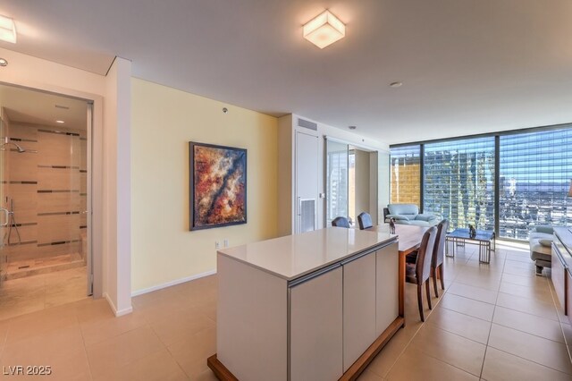 kitchen featuring a kitchen island, white cabinets, a wall of windows, and light tile patterned floors