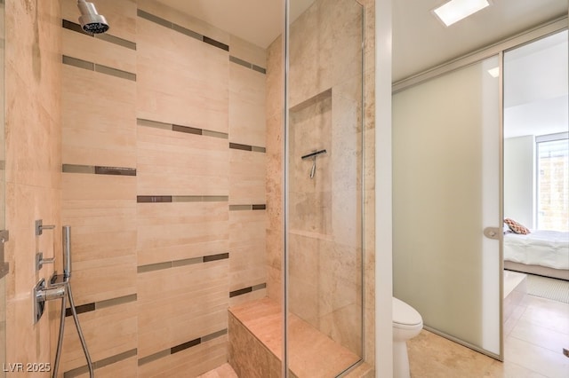 bathroom featuring tiled shower, tile patterned floors, and toilet