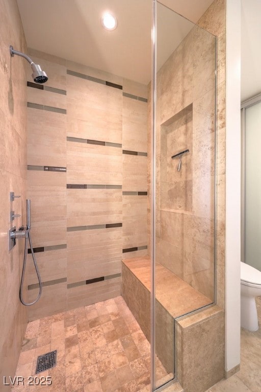 bathroom with a tile shower and toilet