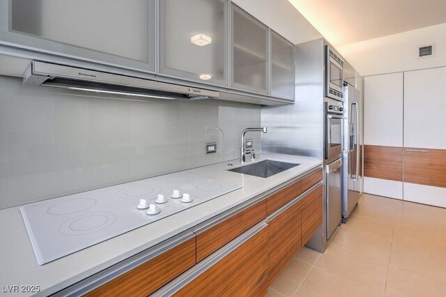 kitchen with light tile patterned flooring, appliances with stainless steel finishes, sink, and range hood