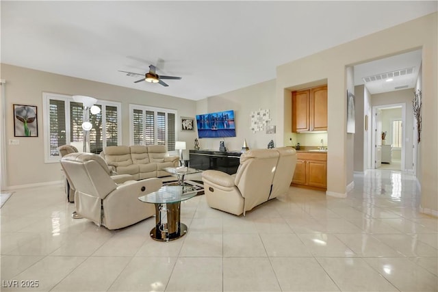 tiled living room with ceiling fan and sink