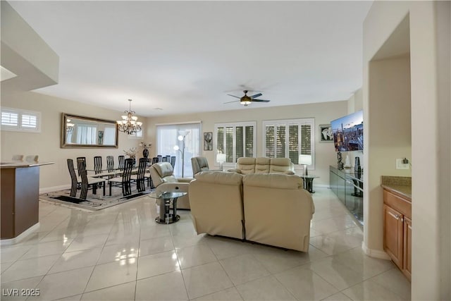 tiled living room with ceiling fan with notable chandelier