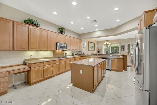 kitchen featuring pendant lighting, appliances with stainless steel finishes, a center island, kitchen peninsula, and a notable chandelier