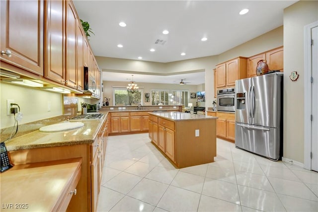 kitchen with a kitchen island, decorative light fixtures, stainless steel appliances, kitchen peninsula, and light tile patterned floors