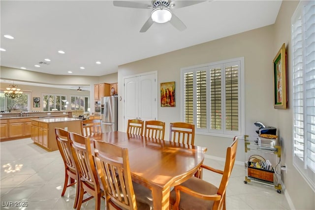 dining space with sink, ceiling fan with notable chandelier, and light tile patterned flooring