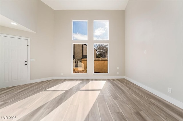 empty room featuring a high ceiling and light wood-type flooring