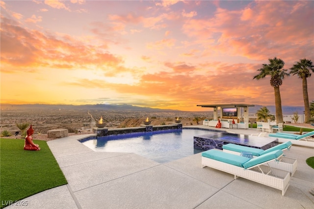 pool at dusk featuring pool water feature and a patio area