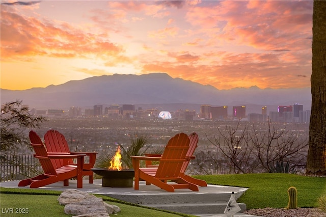 playground at dusk featuring a mountain view, a lawn, and a fire pit