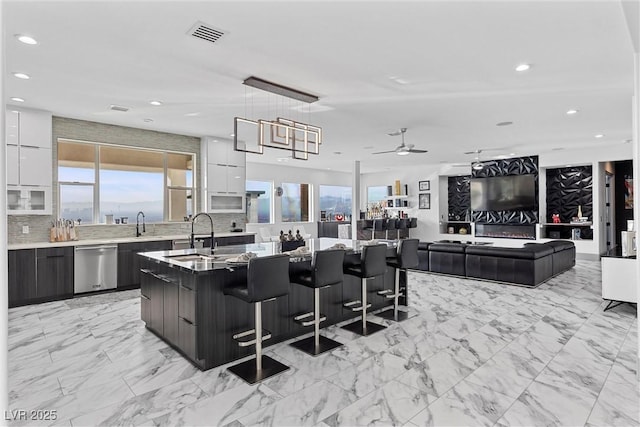 kitchen with ceiling fan, dishwasher, white cabinets, and a kitchen island with sink