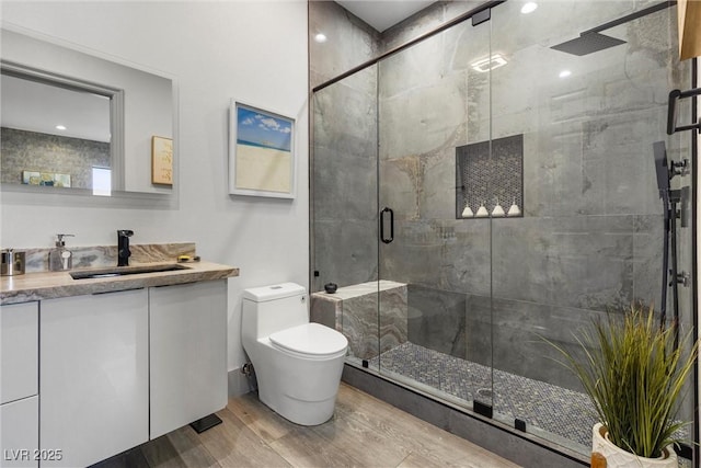 bathroom featuring toilet, vanity, and a shower with shower door