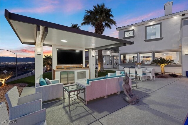 patio terrace at dusk with an outdoor kitchen and an outdoor hangout area