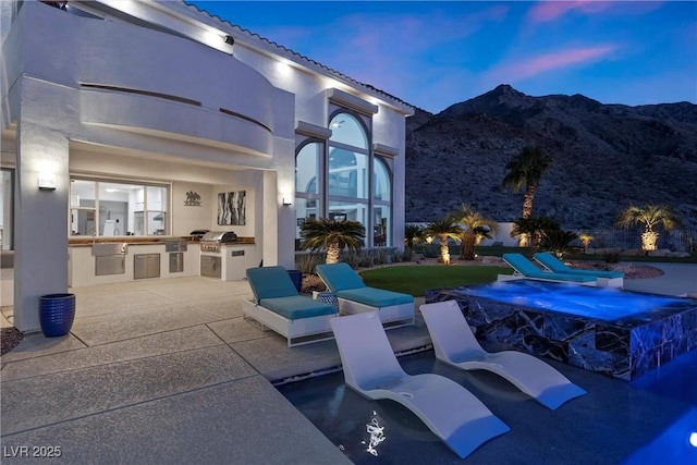 patio terrace at dusk with a mountain view and area for grilling