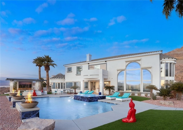 view of swimming pool featuring pool water feature, a patio area, and a fire pit