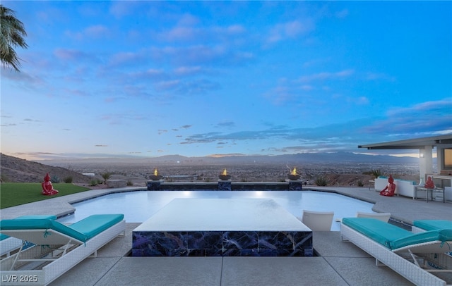 pool at dusk featuring a patio area and a mountain view