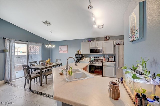 kitchen featuring white cabinetry, sink, hanging light fixtures, light tile patterned floors, and stainless steel appliances